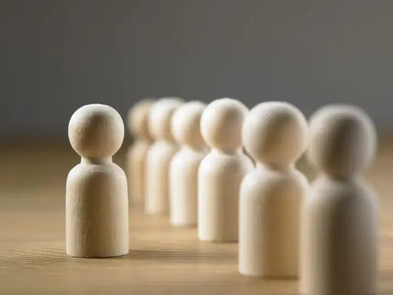 Wooden figures in a row with one to the side