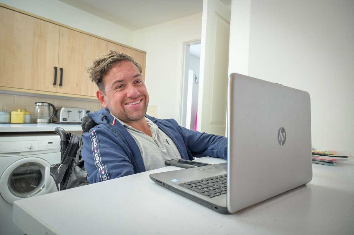 Man in wheelchair with laptop at desk