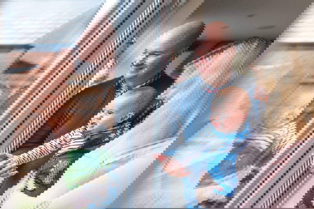 Happy family looking outside window with baby