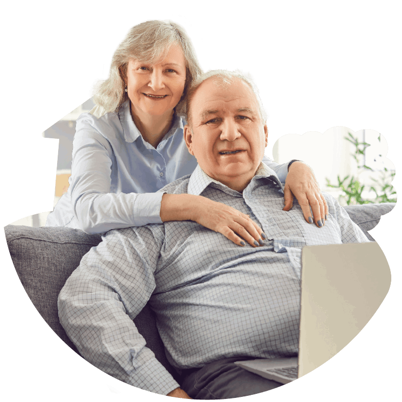 Older couple sitting on a couch with the man having a laptop on his legs