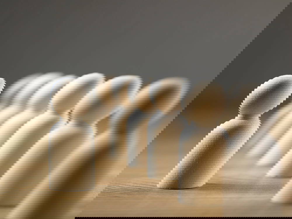 Wooden figures in a row with one to the side